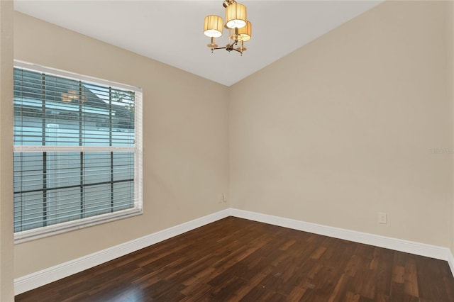 empty room featuring baseboards, dark wood-type flooring, and a notable chandelier