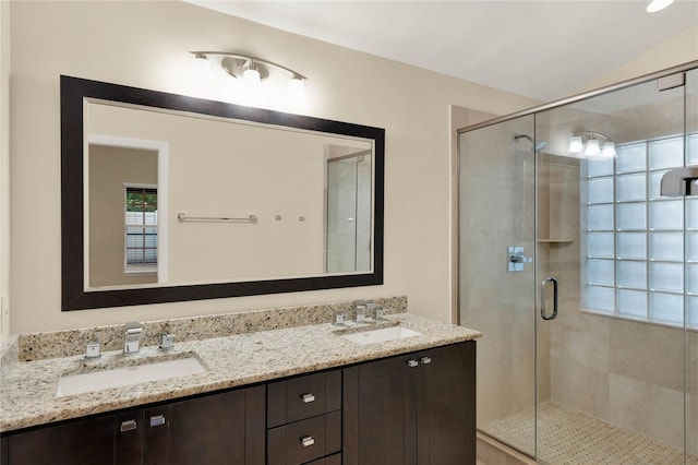 full bathroom with lofted ceiling, a sink, a shower stall, and double vanity