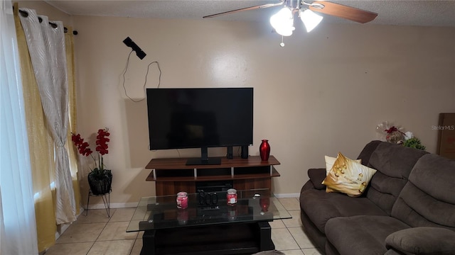 living area with a textured ceiling, ceiling fan, light tile patterned flooring, and baseboards