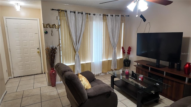 living area with a ceiling fan, light tile patterned flooring, and a textured ceiling