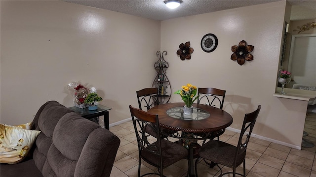 dining area featuring light tile patterned floors, baseboards, and a textured ceiling