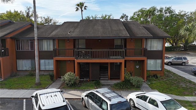 exterior space with uncovered parking and roof with shingles