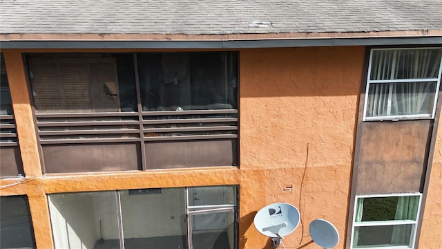 details featuring a shingled roof and stucco siding