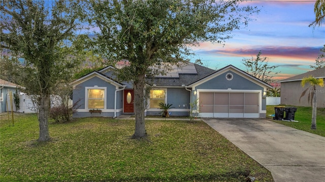 view of front of home with solar panels, stucco siding, an attached garage, driveway, and a front lawn