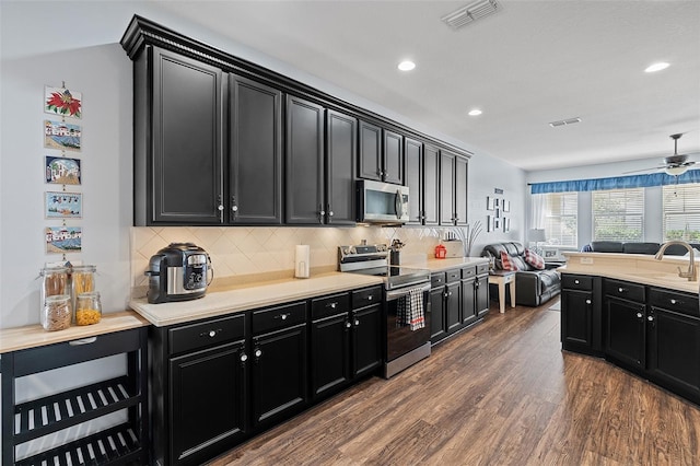 3304 Cat Brier Trl, Harmony, FL 34773 - kitchen featuring dark cabinets, stainless steel appliances, a sink, visible vents, and open floor plan