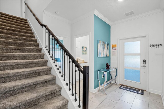 foyer entrance featuring ornamental molding, visible vents, stairs, and light tile patterned floors