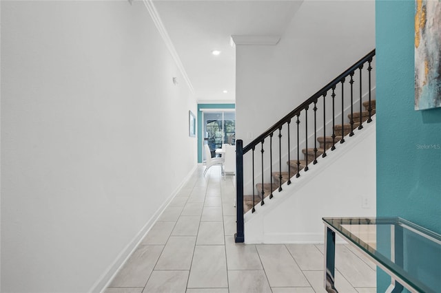 stairway with crown molding, baseboards, and tile patterned floors