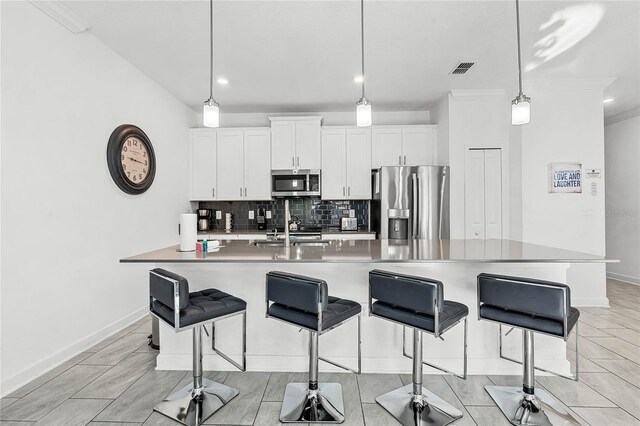 kitchen with a breakfast bar area, visible vents, backsplash, appliances with stainless steel finishes, and white cabinets