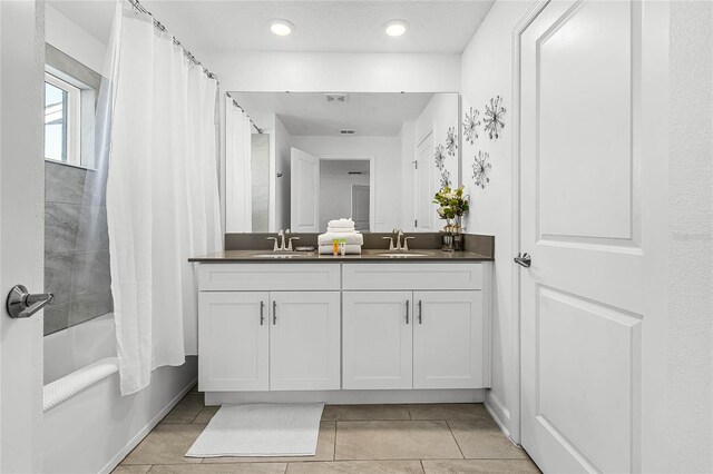 bathroom with double vanity, tile patterned flooring, shower / bath combo, and a sink