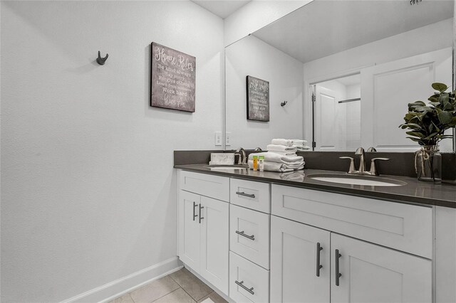 bathroom with a shower, a sink, baseboards, and tile patterned floors