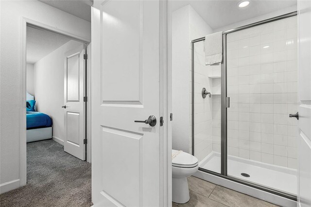 bathroom featuring tile patterned flooring, a shower stall, toilet, and ensuite bathroom