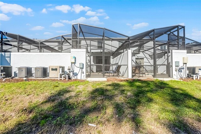 back of house featuring glass enclosure, central AC, and a lawn