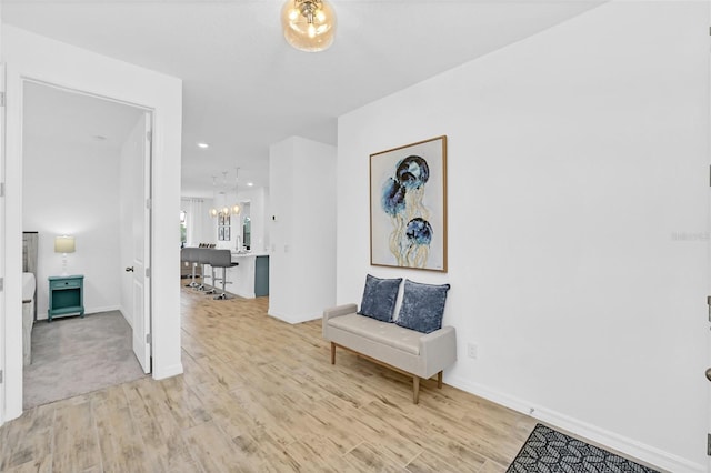 living area with an inviting chandelier, light wood-style flooring, and baseboards