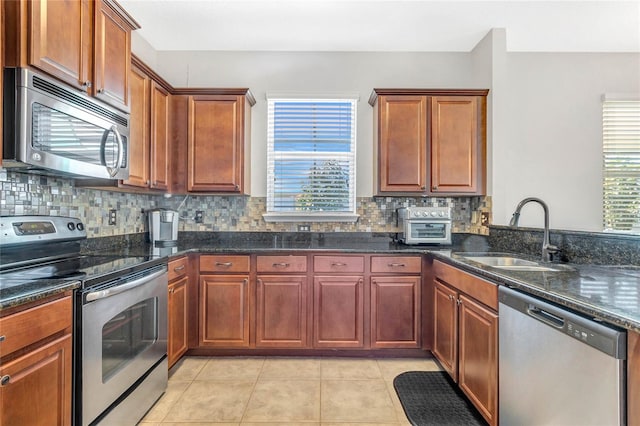 kitchen featuring decorative backsplash, appliances with stainless steel finishes, light tile patterned flooring, plenty of natural light, and a sink