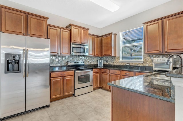 kitchen featuring dark stone countertops, brown cabinets, tasteful backsplash, and appliances with stainless steel finishes