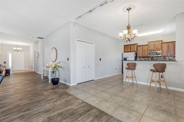 kitchen with visible vents, brown cabinets, a notable chandelier, appliances with stainless steel finishes, and a breakfast bar area