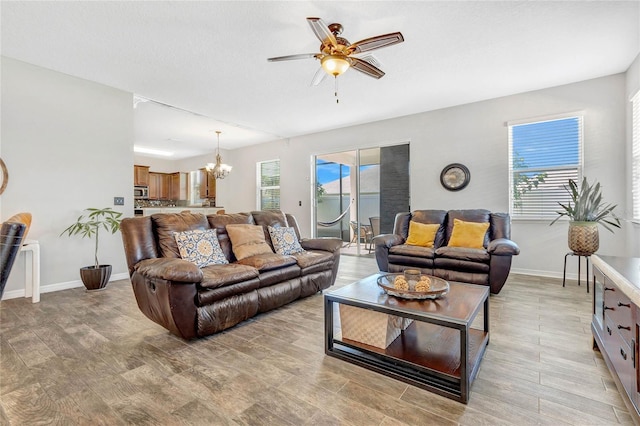 living room with plenty of natural light, ceiling fan with notable chandelier, and baseboards