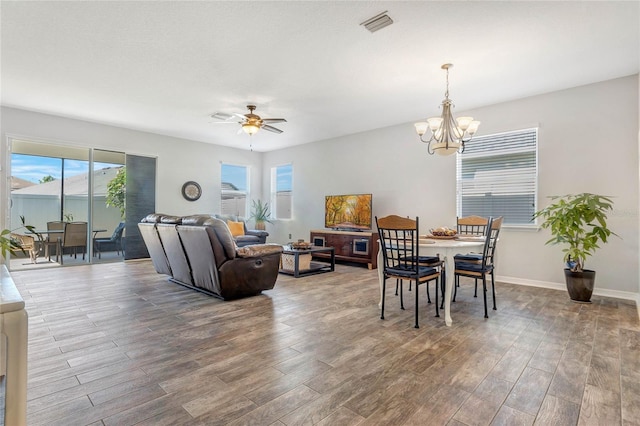 dining area with visible vents, baseboards, wood finished floors, and ceiling fan with notable chandelier