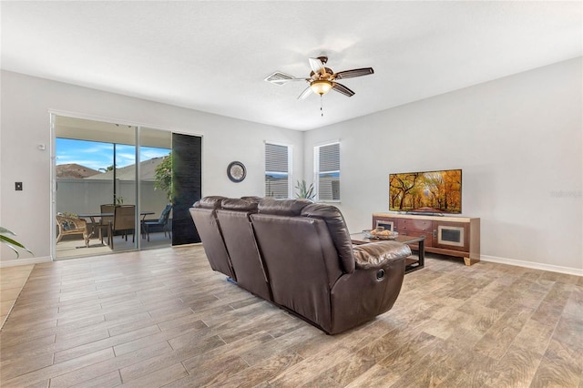 living room with baseboards, visible vents, light wood-type flooring, and ceiling fan