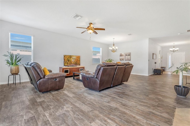 living room with visible vents, ceiling fan with notable chandelier, baseboards, and wood finished floors