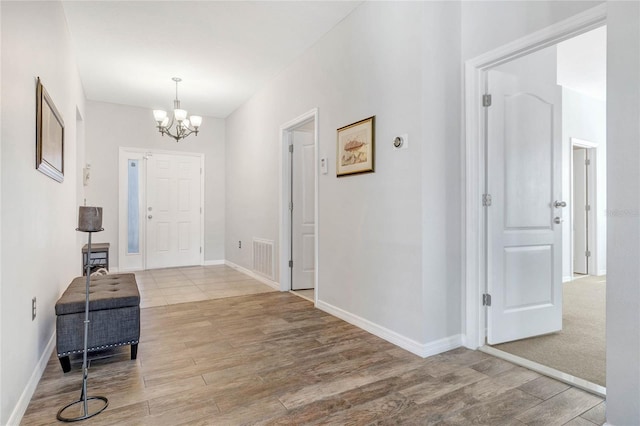 foyer featuring a chandelier, baseboards, and wood finished floors