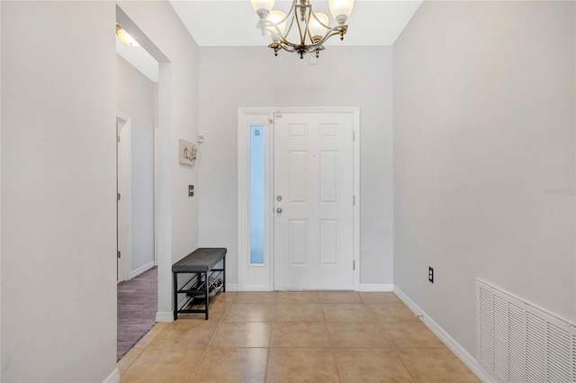 foyer entrance with tile patterned floors, visible vents, baseboards, and a notable chandelier