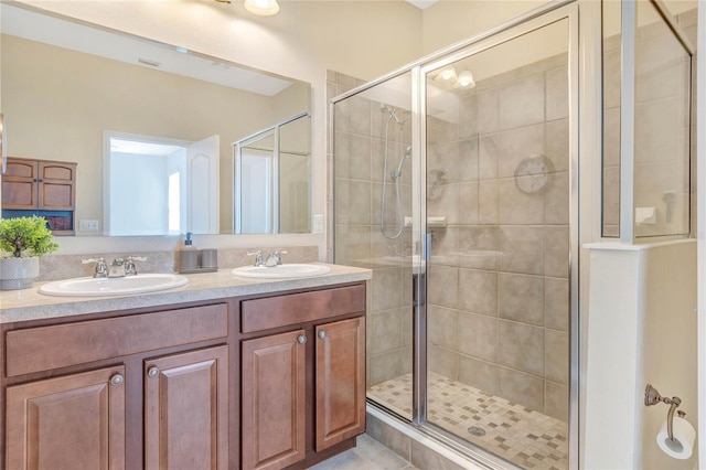 bathroom featuring a shower stall, double vanity, and a sink