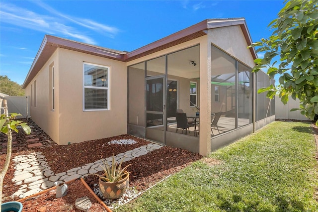 rear view of property with a yard, fence, and stucco siding