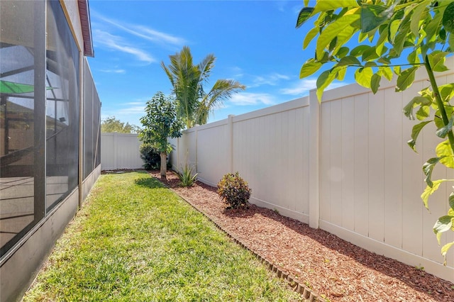 view of yard with glass enclosure and a fenced backyard