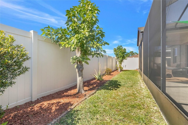 view of yard featuring glass enclosure and a fenced backyard