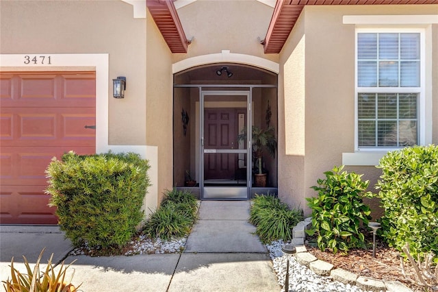 property entrance featuring a garage and stucco siding