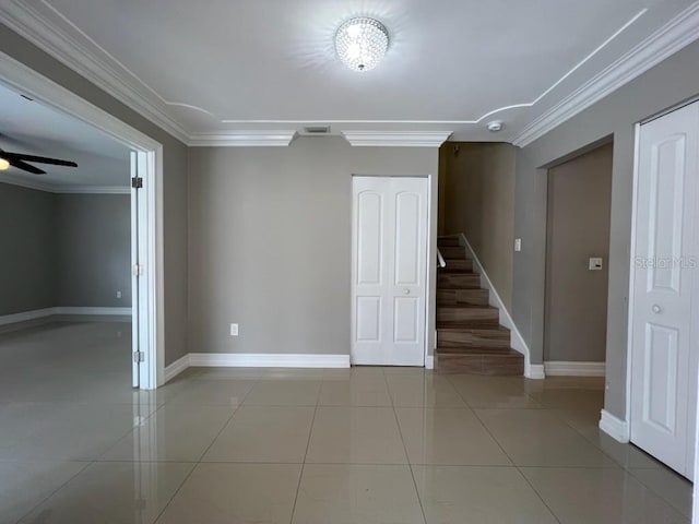 empty room featuring light tile patterned floors, ceiling fan, visible vents, stairway, and crown molding