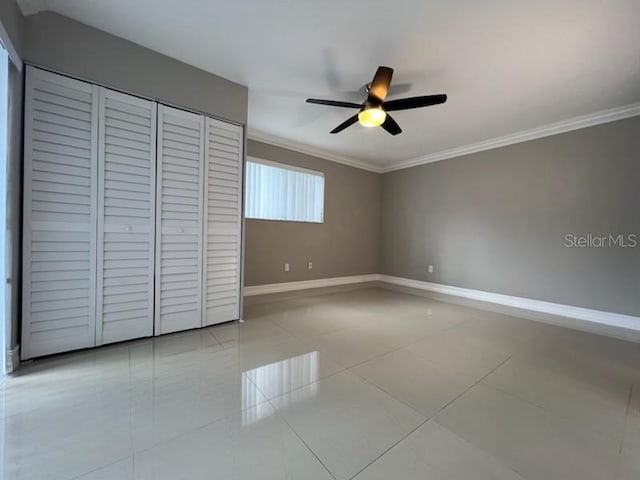 unfurnished bedroom with a ceiling fan, baseboards, a closet, tile patterned floors, and crown molding