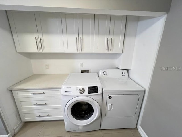 laundry area featuring cabinet space, washer and clothes dryer, baseboards, and light tile patterned floors