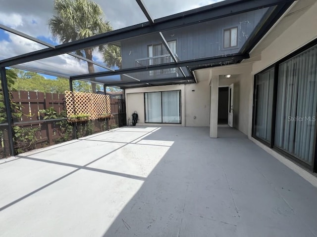 exterior space featuring glass enclosure, a patio, fence, and a balcony