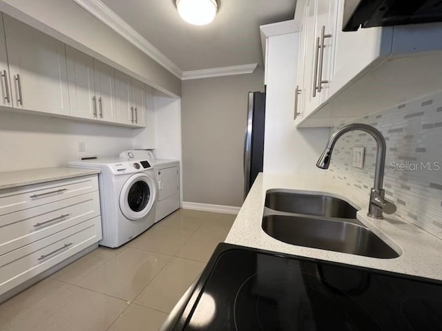 laundry area with cabinet space, light tile patterned floors, crown molding, separate washer and dryer, and a sink