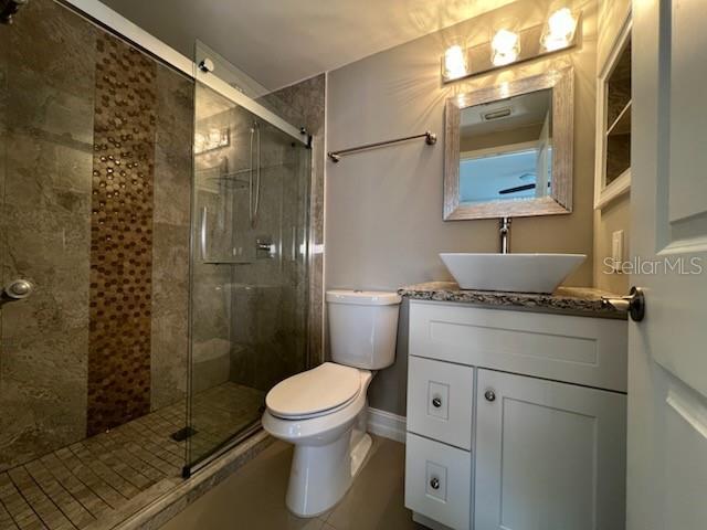 bathroom featuring toilet, a shower stall, and vanity