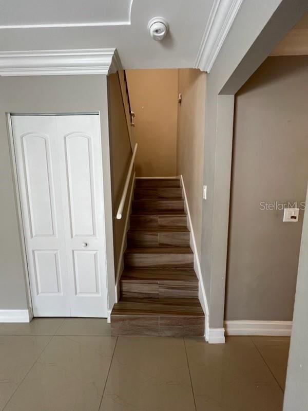 stairs with baseboards, ornamental molding, and tile patterned floors