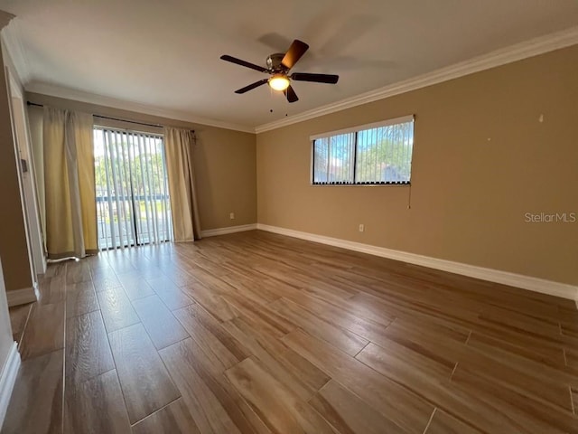 empty room with baseboards, wood finished floors, and crown molding