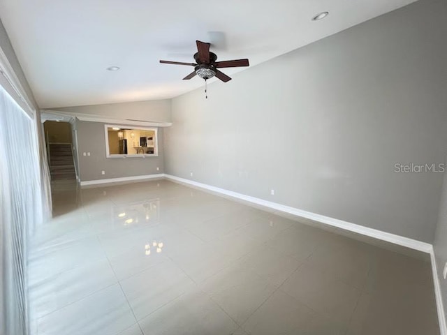 empty room with lofted ceiling, ceiling fan, and baseboards