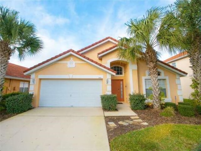 mediterranean / spanish-style house with driveway, an attached garage, a tile roof, and stucco siding