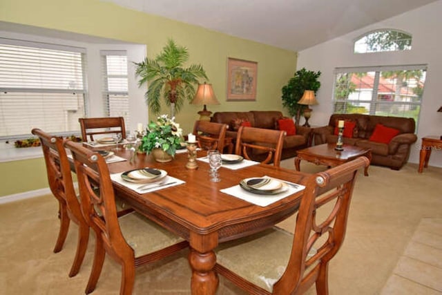 dining space with vaulted ceiling, plenty of natural light, and light colored carpet