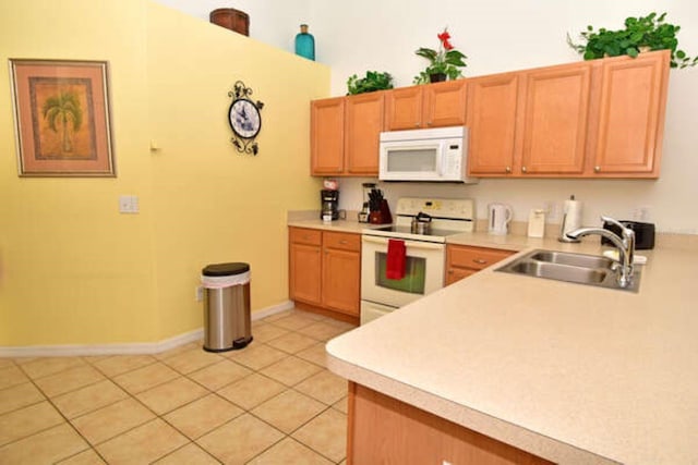 kitchen with light tile patterned floors, light countertops, white appliances, and a sink