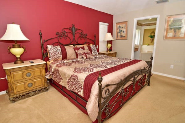 carpeted bedroom with visible vents, baseboards, and ensuite bathroom