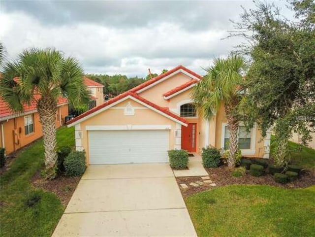 mediterranean / spanish-style home with a garage, driveway, a front yard, and stucco siding