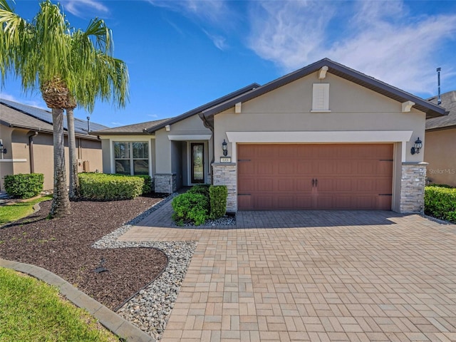 view of front of property with stone siding, decorative driveway, and stucco siding