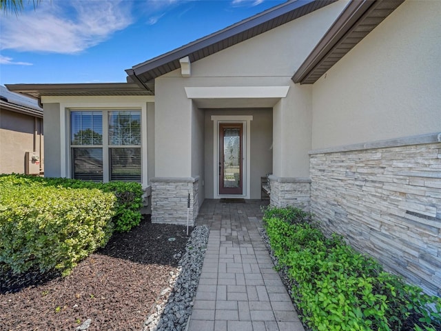 doorway to property with stone siding and stucco siding