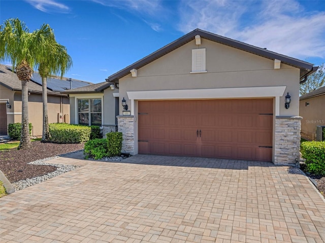 view of front facade with stone siding, decorative driveway, and stucco siding