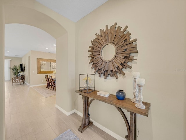 corridor with arched walkways, light tile patterned floors, recessed lighting, and baseboards