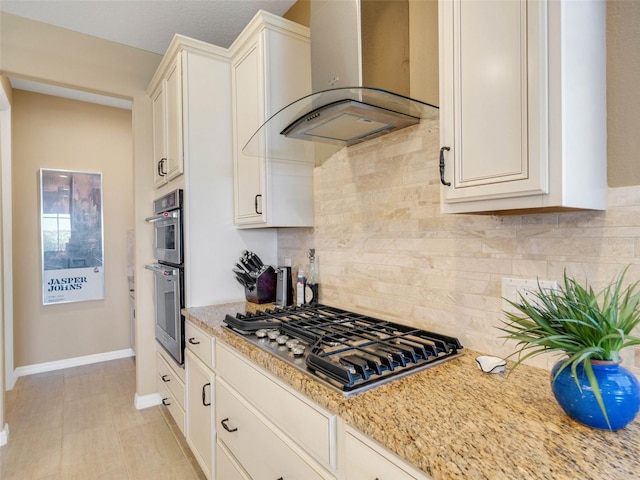 kitchen featuring wall chimney exhaust hood, appliances with stainless steel finishes, light stone counters, and tasteful backsplash